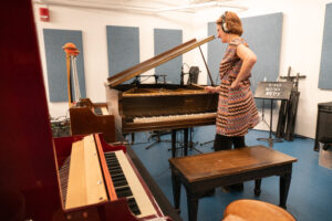 Stacey Barelos in the recording studio next to three keyboards.