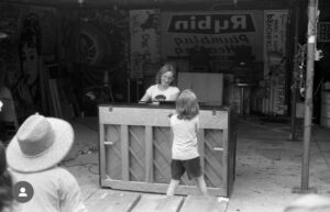 A picture of Stacey Barelos about to play the piano as others destroy it with sledgehammers.